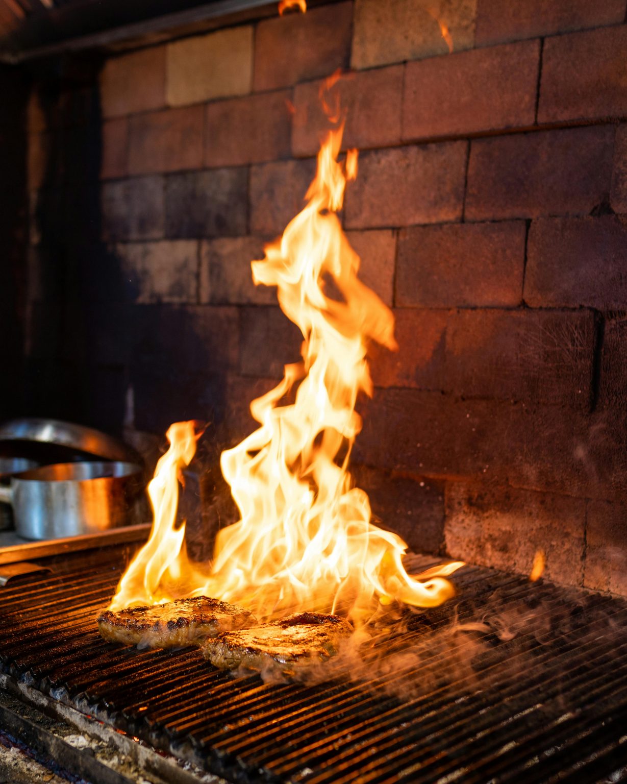 Juicy steaks on a flaming grill in a rustic kitchen setting, showcasing the art of grilling.